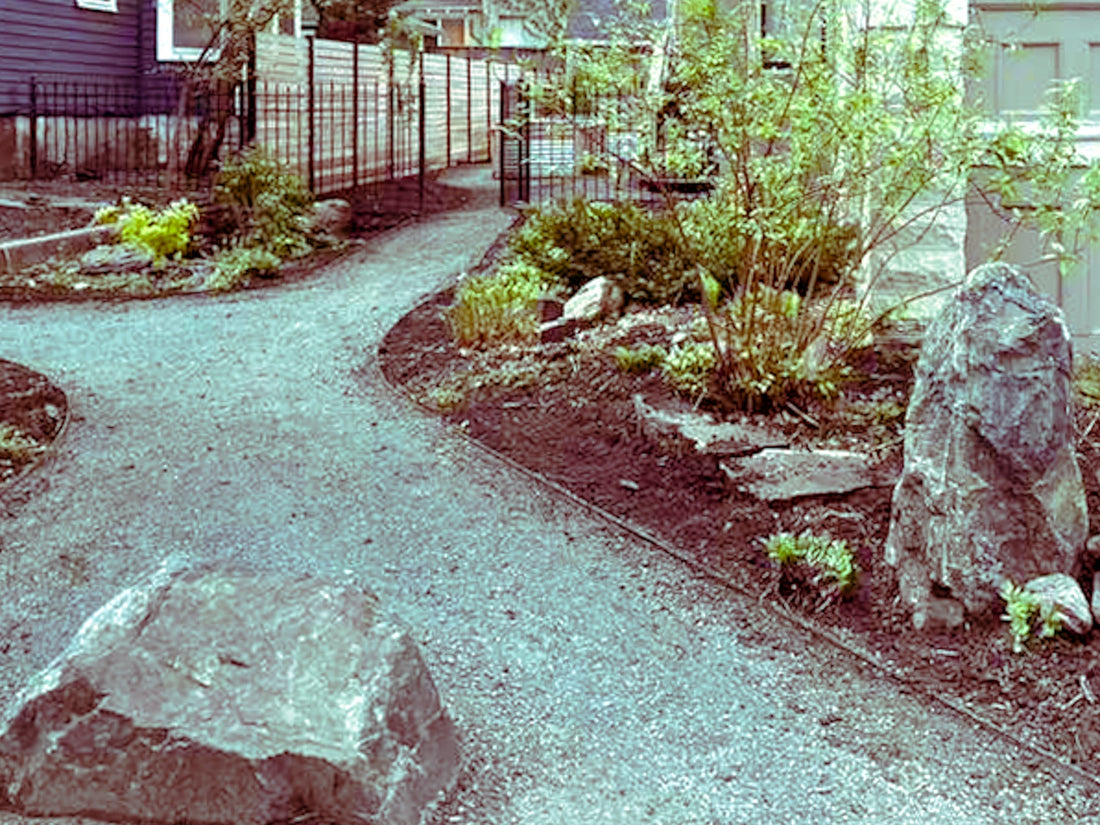 Custom garden walkway installation in Minneapolis with curved gravel path, natural boulder accents, and fresh mulch beds.
